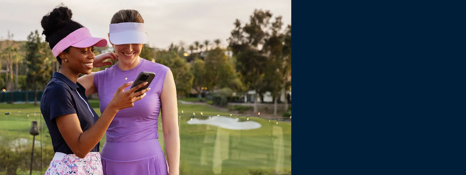Two woman at a golf club looking at a phone.
