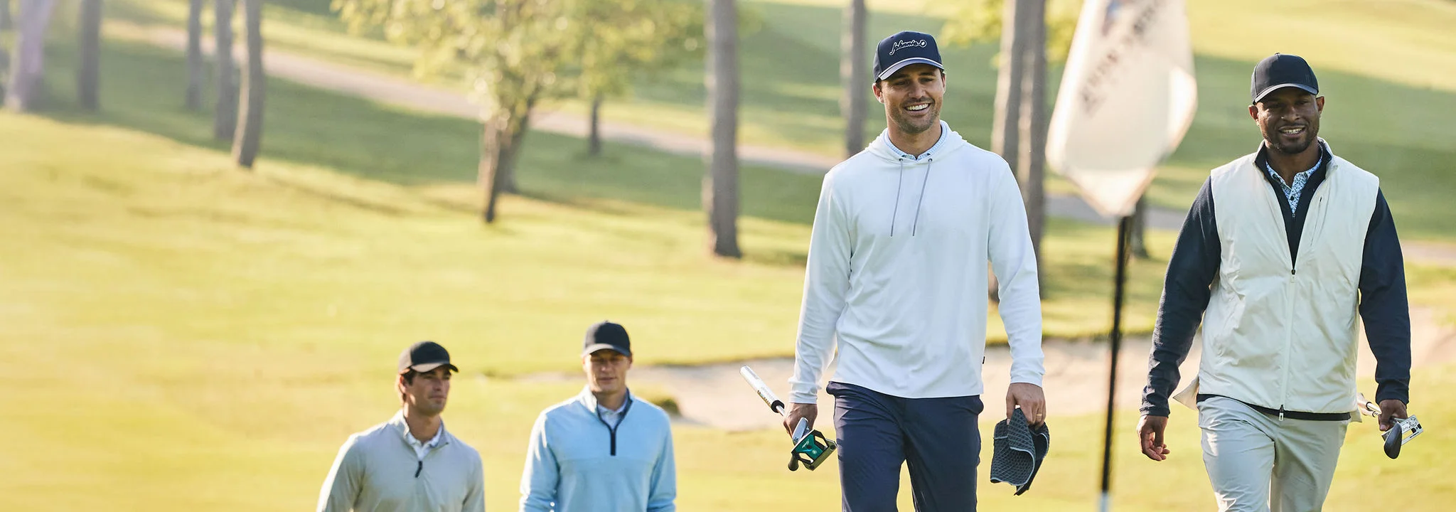 Four men walking up to a putting green.