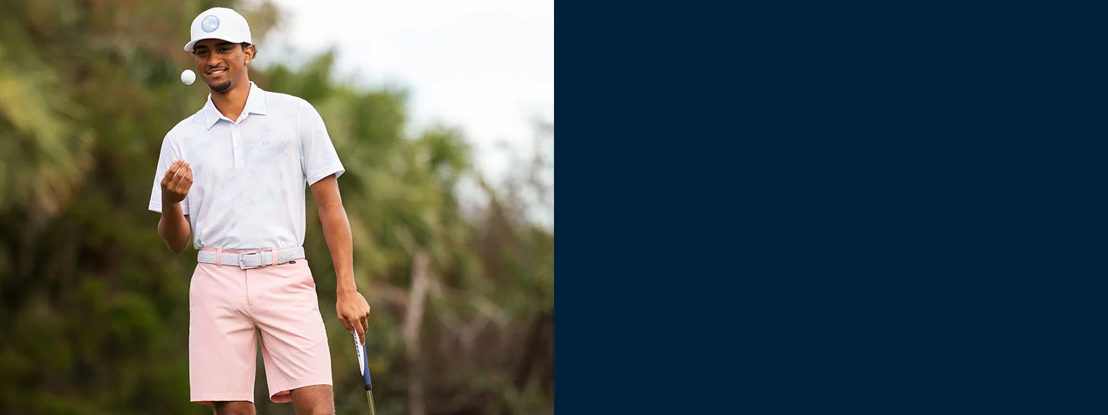 A man throwing a golf ball in the air while waiting to tee off. 