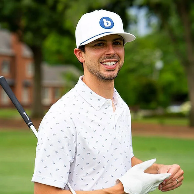Smiling golfer holding club on green course