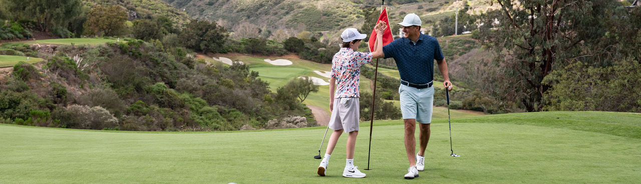 older and younger man high fiving on course