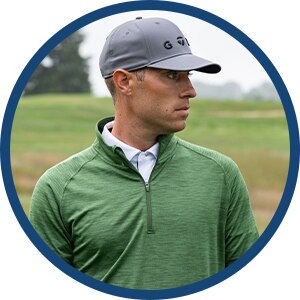 A golfer wearing a red shirt and blue shorts.