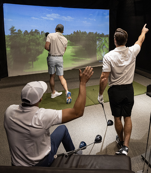 A group of golfers playing a round in the hitting bay.