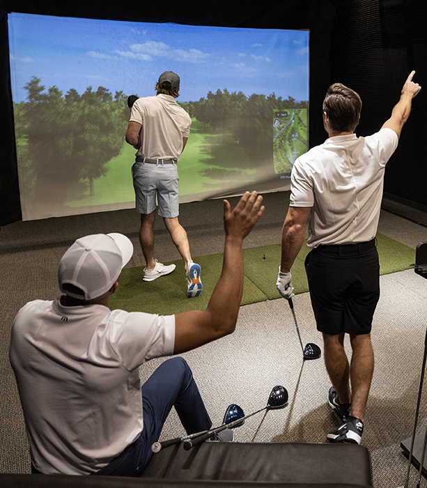 A group of golfers playing a round in the hitting bay.